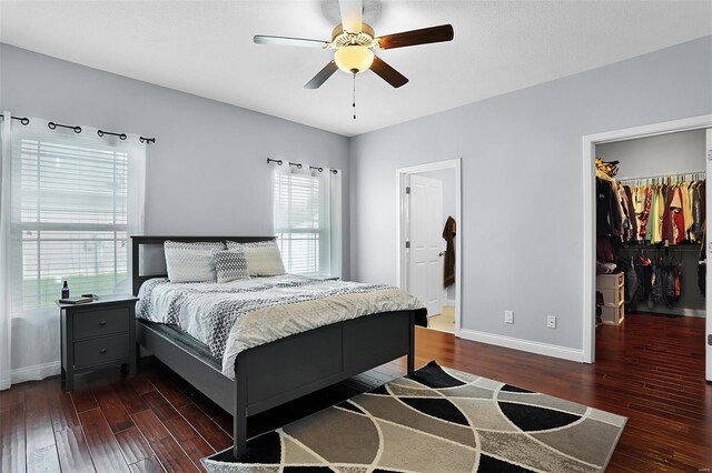 bedroom with baseboards, a closet, a spacious closet, and hardwood / wood-style flooring