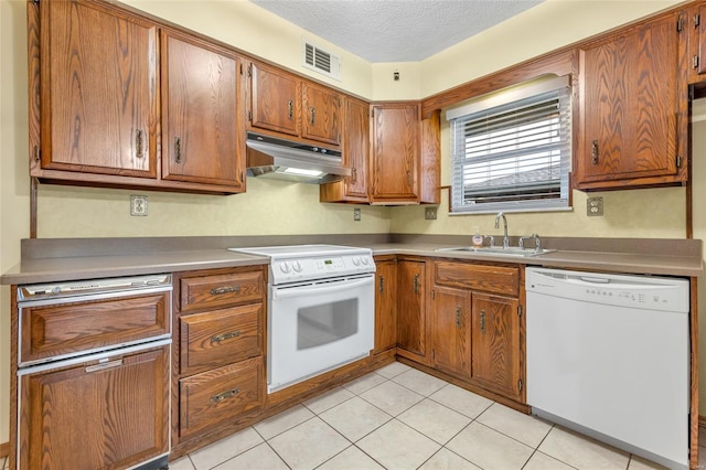 kitchen with visible vents, a sink, white appliances, a textured ceiling, and under cabinet range hood