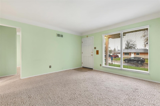 empty room featuring carpet, visible vents, and baseboards