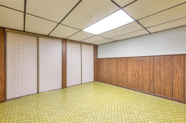 interior space with wooden walls and a drop ceiling