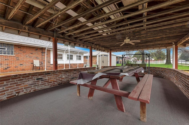 view of patio featuring a shed, ceiling fan, fence, and an outdoor structure