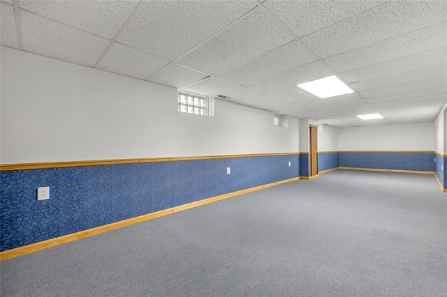 below grade area featuring carpet flooring, visible vents, a drop ceiling, and baseboards