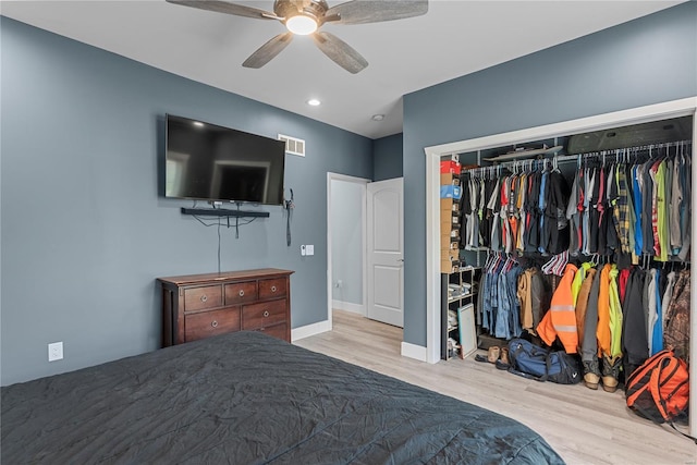 bedroom with wood finished floors, visible vents, a closet, baseboards, and ceiling fan