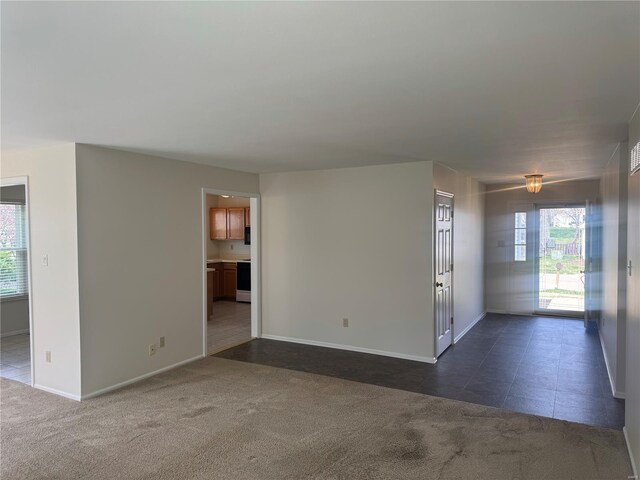 empty room with baseboards and dark carpet