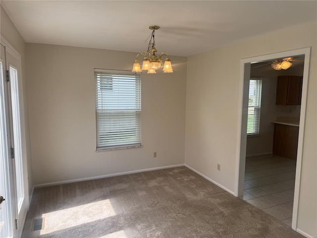 carpeted empty room featuring baseboards, visible vents, tile patterned flooring, and a notable chandelier