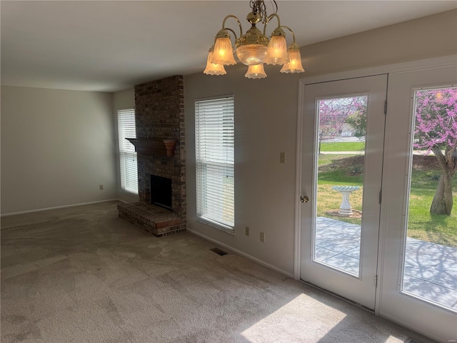 unfurnished living room featuring an inviting chandelier, carpet flooring, baseboards, visible vents, and a brick fireplace
