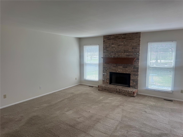 unfurnished living room with baseboards, carpet floors, visible vents, and a brick fireplace