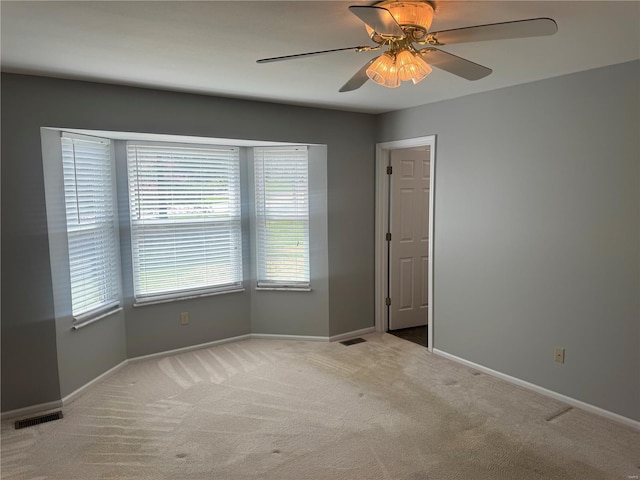 spare room with baseboards, visible vents, ceiling fan, and carpet flooring