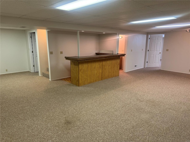 bar with a dry bar, carpet floors, a drop ceiling, and baseboards