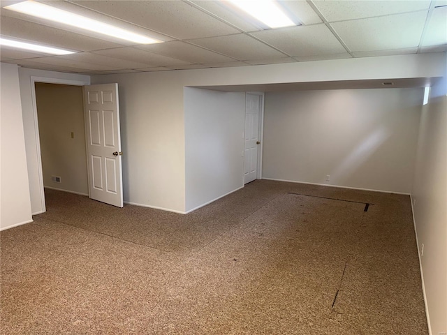 finished below grade area featuring baseboards, visible vents, a drop ceiling, and carpet
