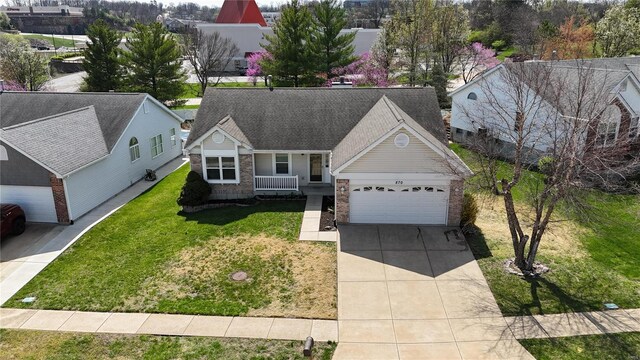 view of front of house with an attached garage, a shingled roof, concrete driveway, and a front yard