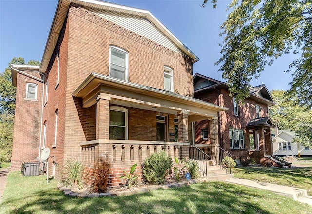 view of front facade with brick siding, a front lawn, and a porch