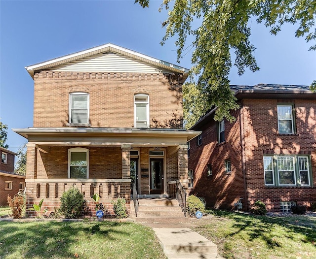 view of front of house featuring brick siding, a front lawn, and a porch