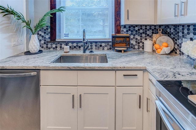 kitchen with dishwasher, white cabinetry, a sink, light stone counters, and backsplash