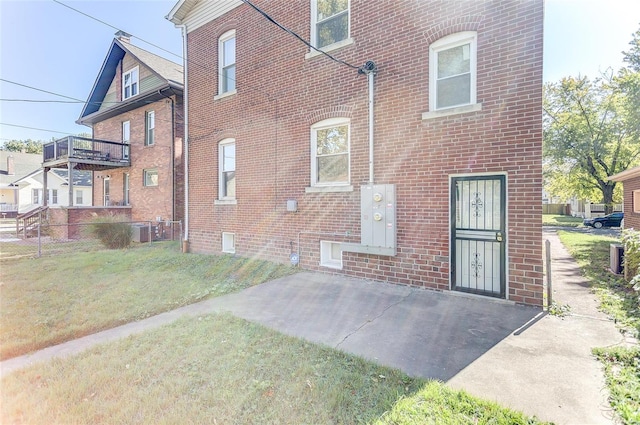 back of house featuring central air condition unit, brick siding, and a yard