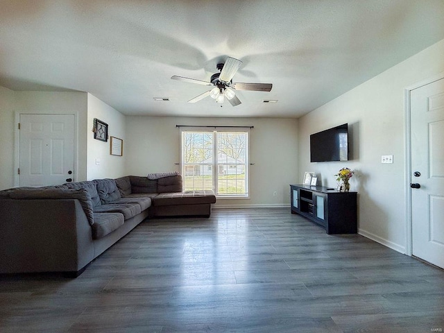 living area featuring visible vents, baseboards, a ceiling fan, and wood finished floors