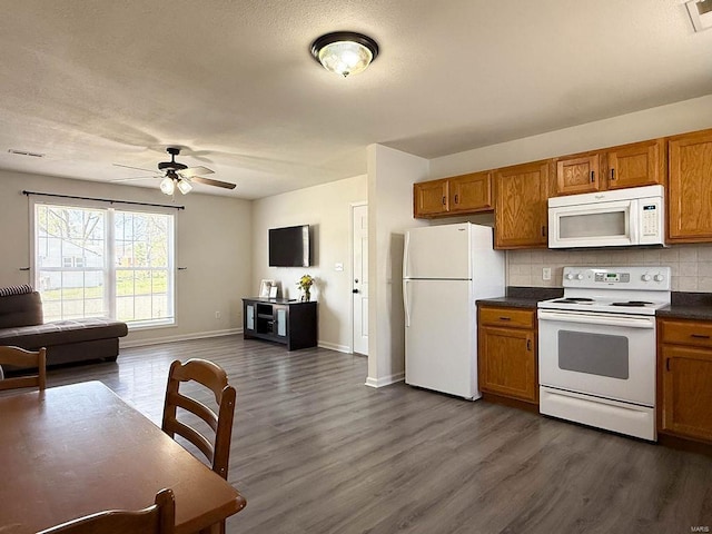 kitchen featuring brown cabinets, dark countertops, white appliances, and dark wood-style floors