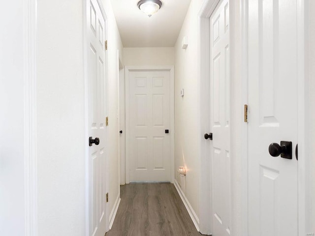 corridor with wood finished floors and baseboards