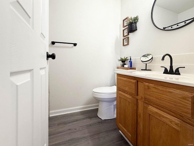 bathroom featuring toilet, wood finished floors, vanity, and baseboards