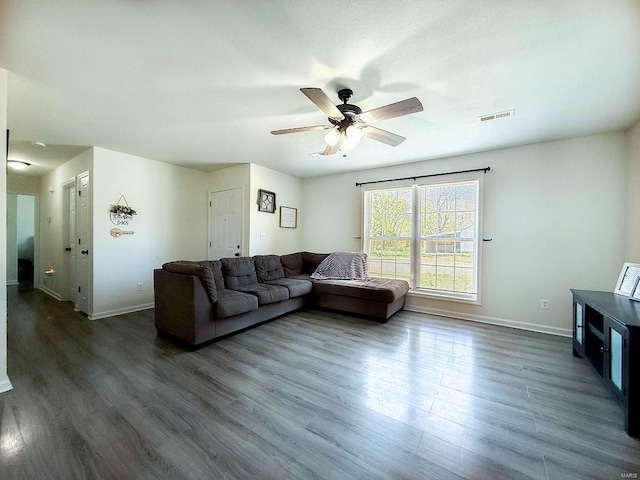 living room featuring visible vents, dark wood-style flooring, baseboards, and ceiling fan