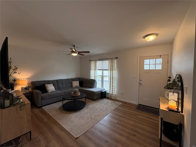 living area featuring baseboards, ceiling fan, and dark wood finished floors