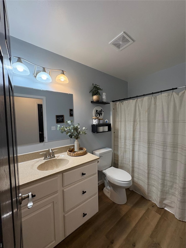 full bathroom featuring a shower with shower curtain, toilet, vanity, wood finished floors, and visible vents