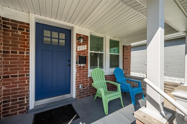 doorway to property featuring brick siding and a porch