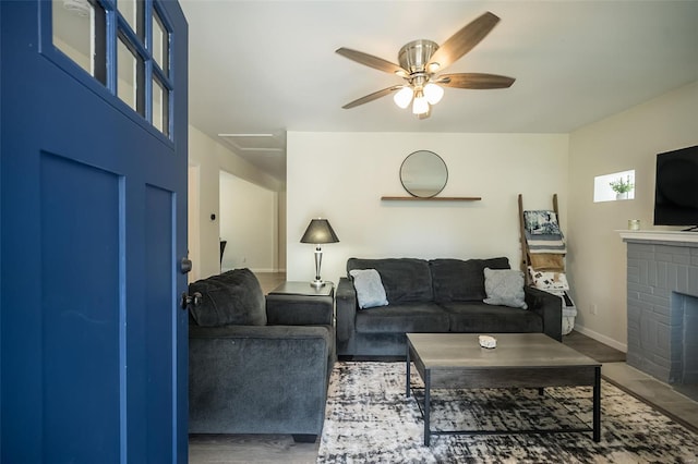 living area with a fireplace, baseboards, and a ceiling fan