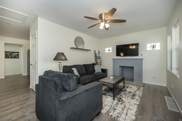 living area with visible vents, baseboards, a ceiling fan, and wood finished floors