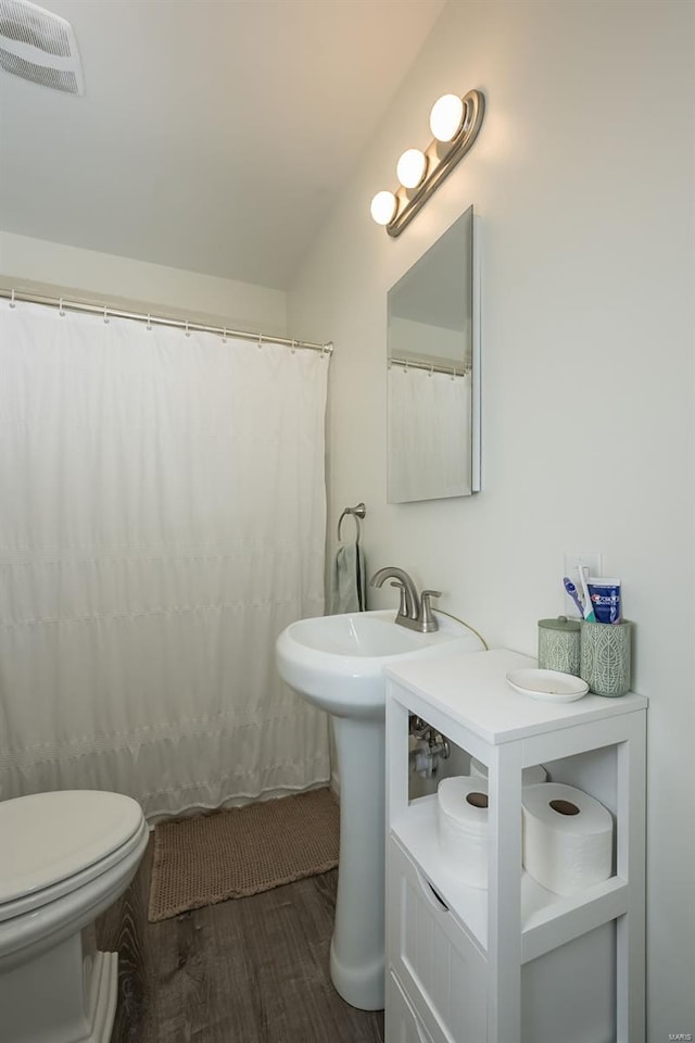 bathroom with toilet, wood finished floors, a shower with shower curtain, and visible vents