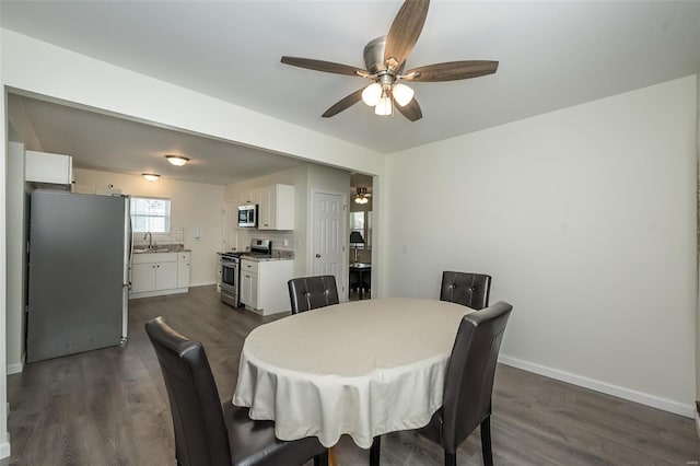dining space featuring dark wood-type flooring, baseboards, and a ceiling fan
