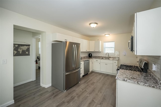kitchen with tasteful backsplash, a sink, dark wood finished floors, white cabinetry, and stainless steel appliances