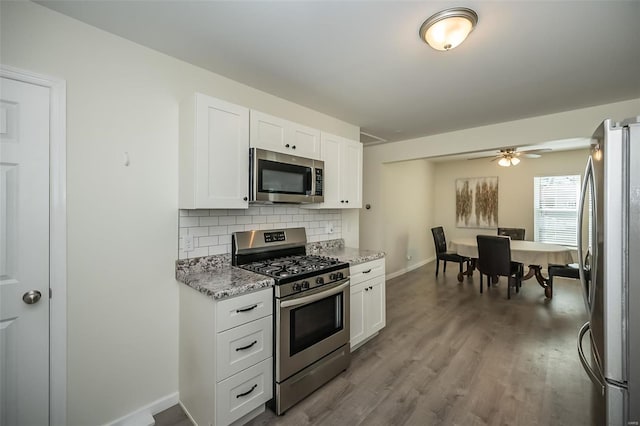 kitchen with light stone counters, white cabinetry, backsplash, stainless steel appliances, and wood finished floors
