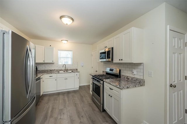 kitchen with decorative backsplash, a sink, light stone countertops, and stainless steel appliances