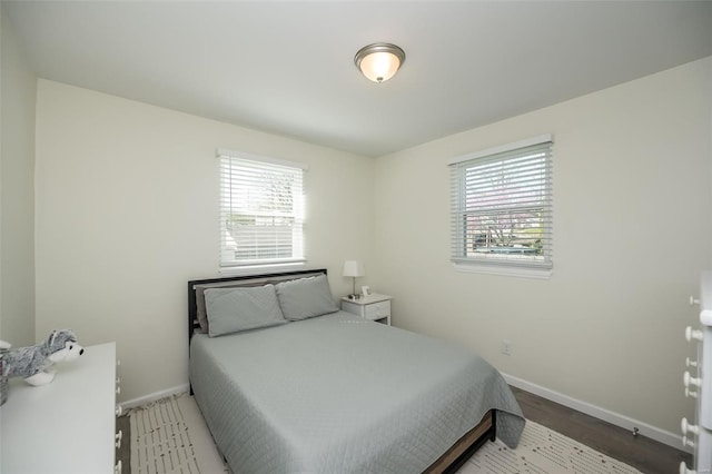 bedroom with multiple windows, baseboards, and wood finished floors