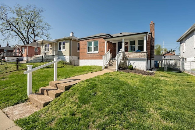 view of front facade featuring a front yard, brick siding, fence, and covered porch