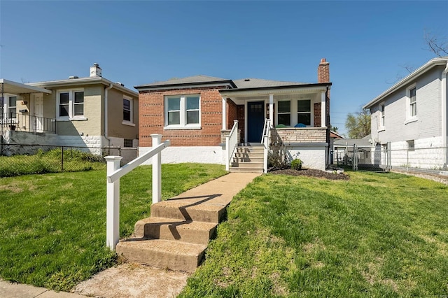 view of front of house featuring brick siding, fence, and a front lawn