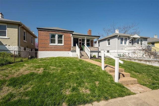 bungalow with brick siding, fence, a front lawn, and covered porch