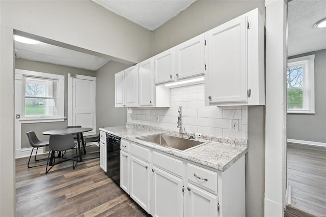 kitchen with a wealth of natural light, light countertops, a sink, and black dishwasher