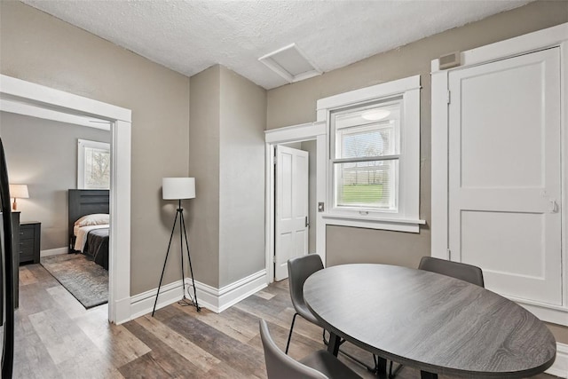 dining space featuring baseboards, attic access, wood finished floors, and a textured ceiling
