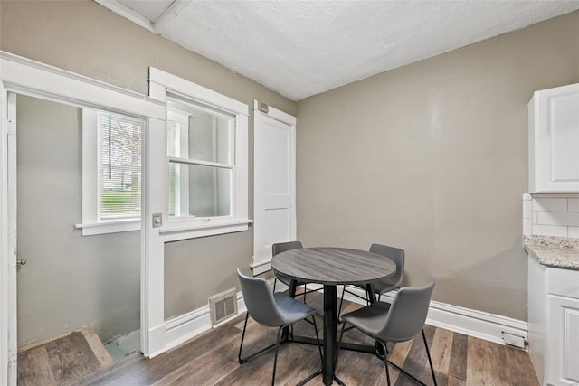dining space with visible vents, baseboards, a textured ceiling, and dark wood-style floors