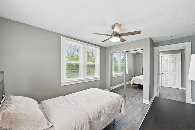 bedroom with ceiling fan, a textured ceiling, a closet, wood finished floors, and baseboards