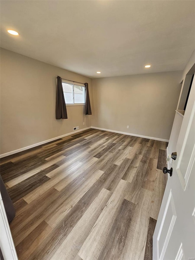 spare room with baseboards, recessed lighting, and dark wood-style flooring