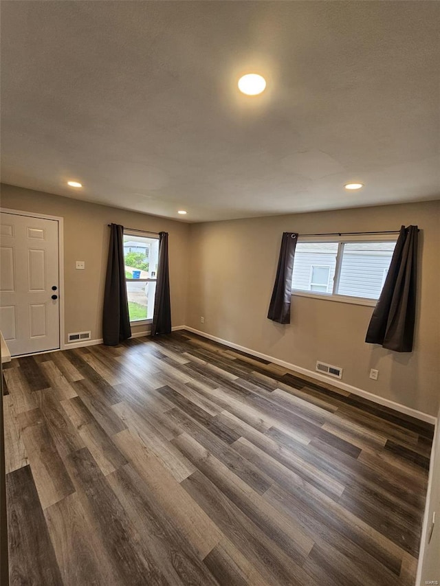 unfurnished room with baseboards, dark wood-style flooring, visible vents, and recessed lighting
