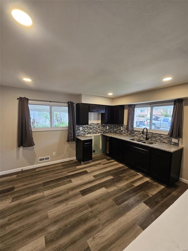 kitchen with recessed lighting, dark wood-style floors, dark cabinetry, a sink, and light stone countertops
