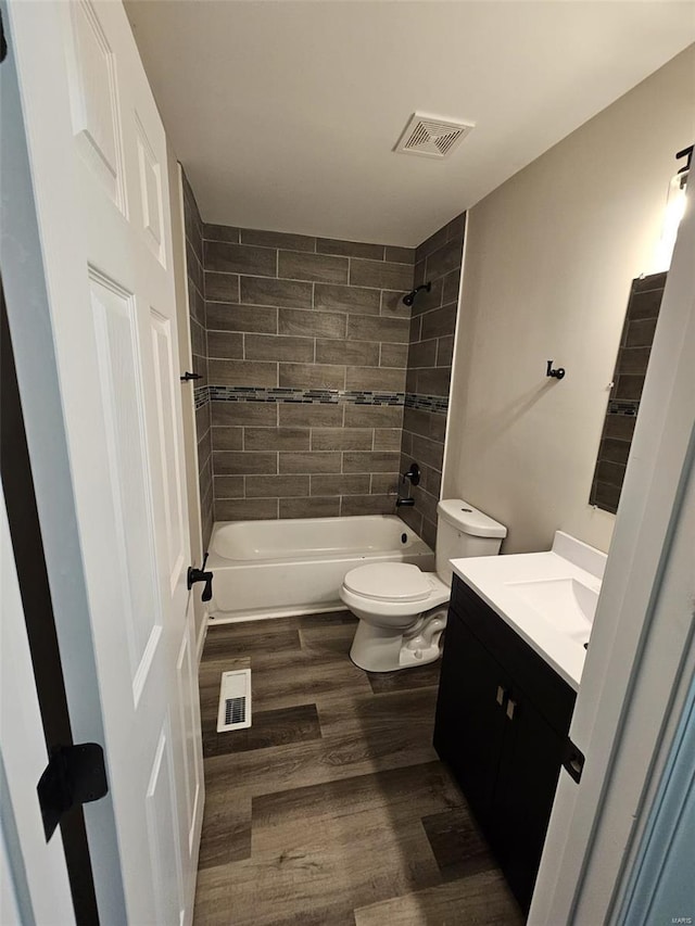 full bathroom featuring toilet, shower / bathtub combination, wood finished floors, and visible vents