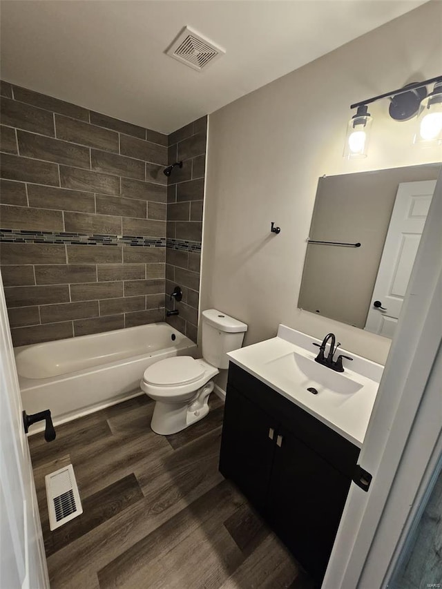 bathroom featuring toilet, visible vents, shower / bath combination, wood finished floors, and vanity