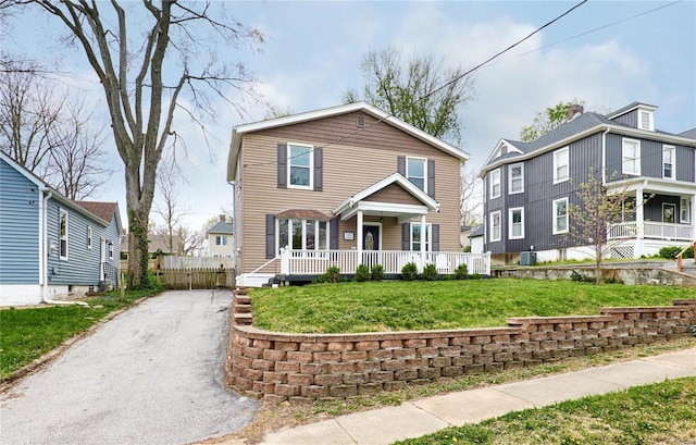 traditional-style home with aphalt driveway, a porch, and a front yard