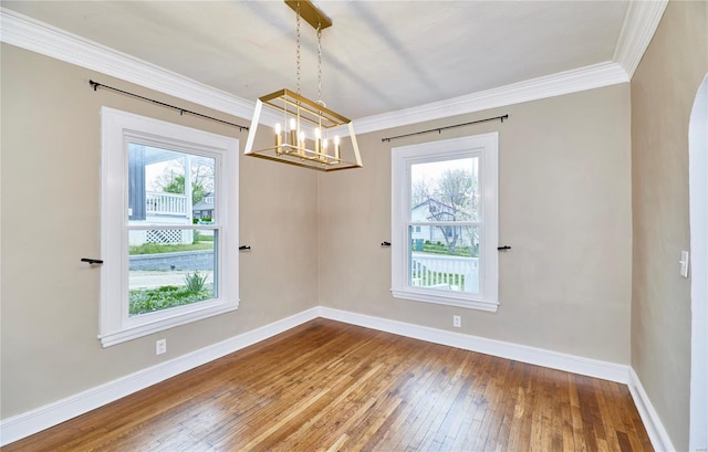 unfurnished dining area featuring baseboards, hardwood / wood-style flooring, an inviting chandelier, and a healthy amount of sunlight