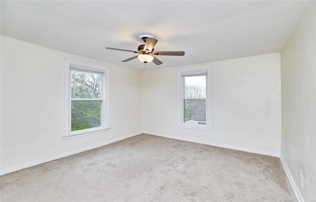 carpeted spare room with baseboards, a ceiling fan, and a healthy amount of sunlight